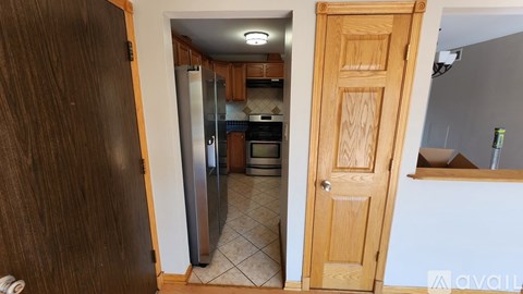 A kitchen with a refrigerator and wooden cabinets.