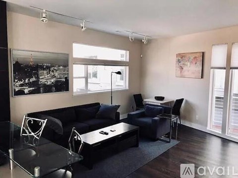 A living room with a black couch and a glass table.