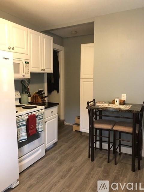 A kitchen with white cabinets and a black countertop with a table and two chairs.