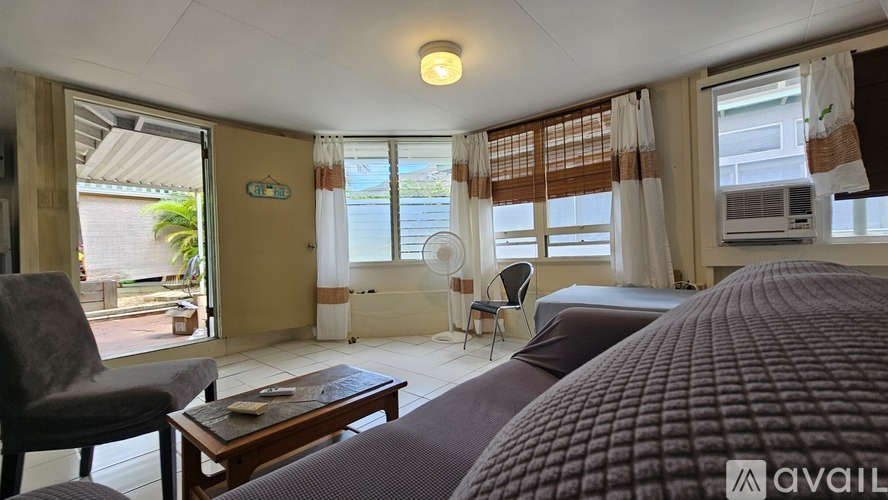 A bedroom with a large bed and a chair in front of a sliding glass door.