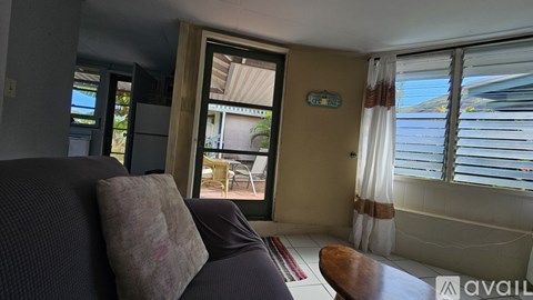 A living room with a couch and a window with a view of the outside.