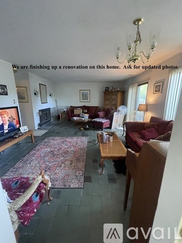 A living room with a rug, a couch, a coffee table, and a chandelier.