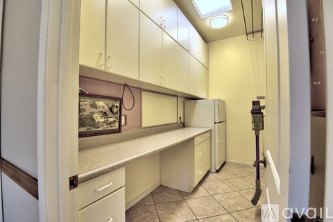 A kitchen with white cabinets and a skylight.