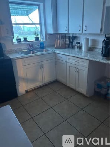A kitchen with white cabinets and a tiled floor.