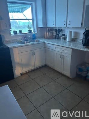 A kitchen with white cabinets and a tiled floor.