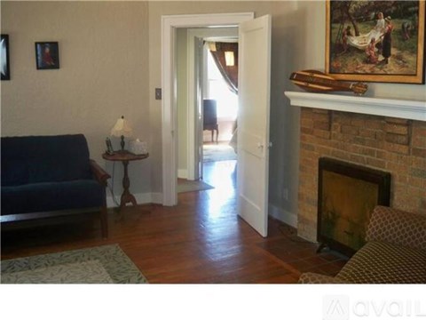 A living room with a blue couch, a lamp, a fireplace, and a painting on the wall.