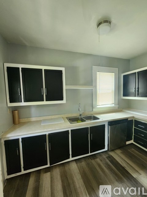 A kitchen with black and white cabinets and a wooden floor.