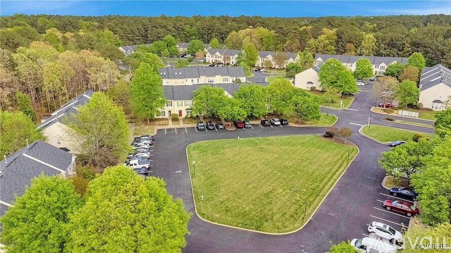 A bird's eye view of a residential area with houses, cars, and a green lawn.