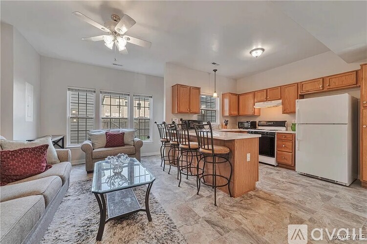 A well-lit kitchen and living room with a glass coffee table in the middle.