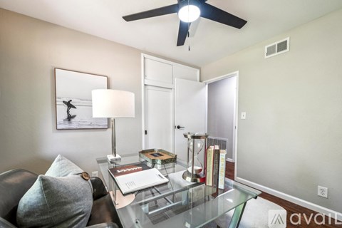 A living room with a couch, a coffee table, a ceiling fan, and a painting on the wall.