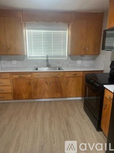 A kitchen with wooden cabinets and a black stove top oven.