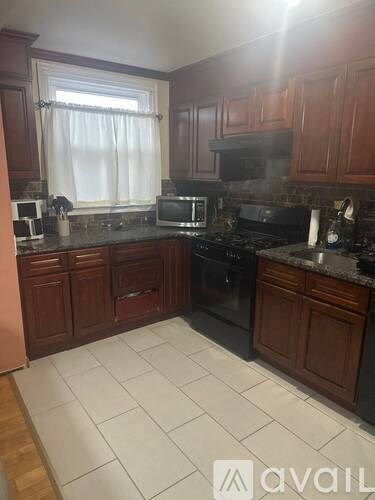 A kitchen with dark wood cabinets and black appliances.