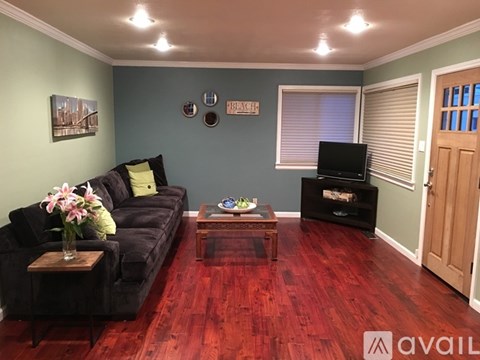 A living room with a black couch and a wooden coffee table.