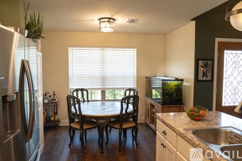 A kitchen with a table and chairs in front of a window.