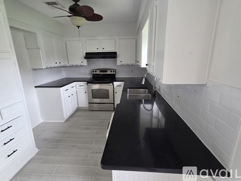 A kitchen with white cabinets and a black countertop.