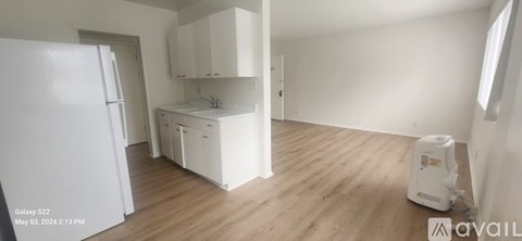 A kitchen with white cabinets and a white fridge is available for rent.