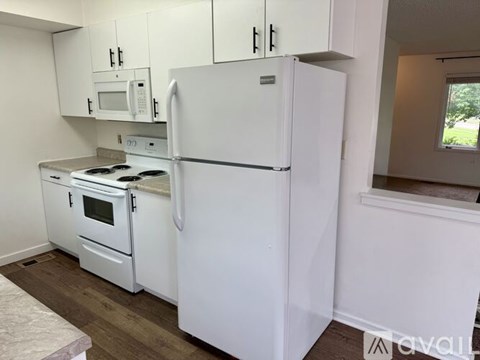 A white refrigerator stands in a kitchen next to a stove.