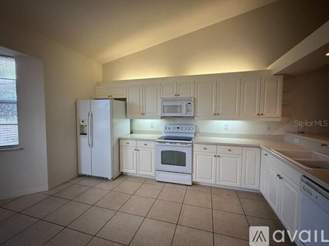 A kitchen with white appliances and cabinets.