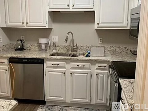A kitchen with white cabinets and a granite countertop.