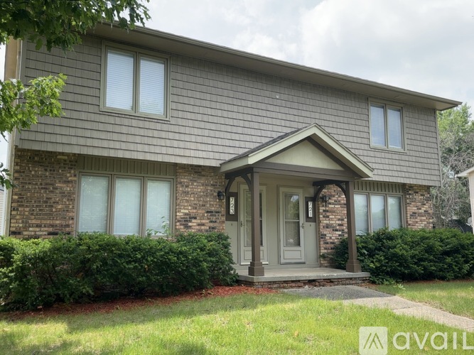 A house with a grey front and a green lawn.