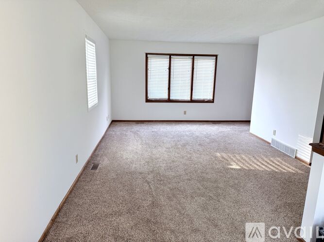 A room with a carpeted floor and a window with blinds.