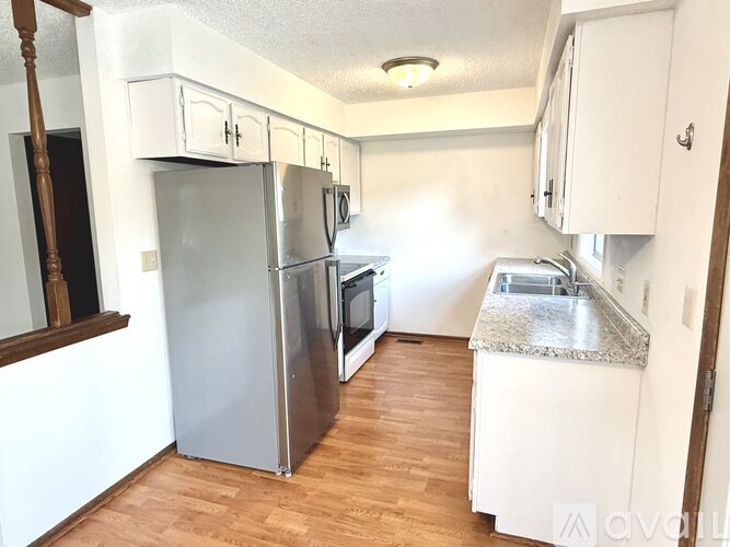 A kitchen with a refrigerator, oven, sink, and cabinets.