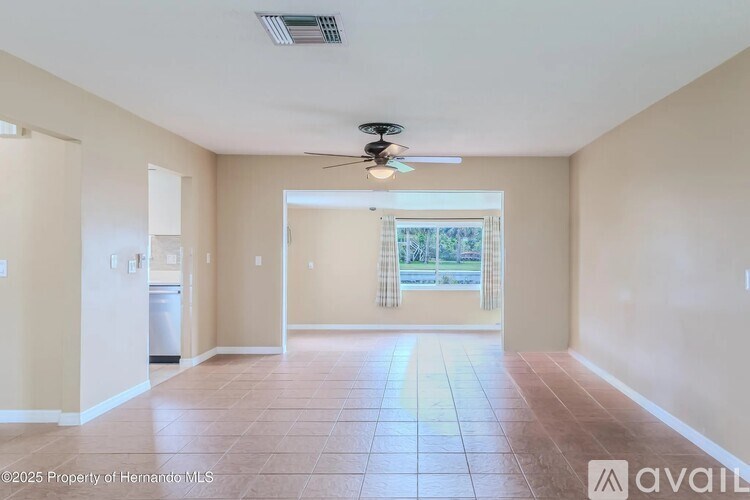 A spacious room with a ceiling fan and tiled flooring.