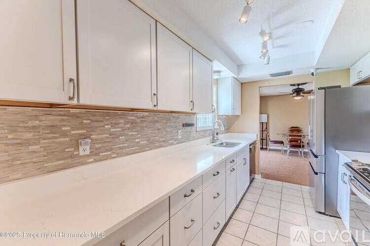 A kitchen with white cabinets and a tiled floor.