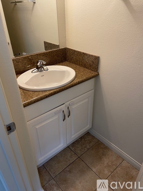 A bathroom with a brown counter top and a white sink.