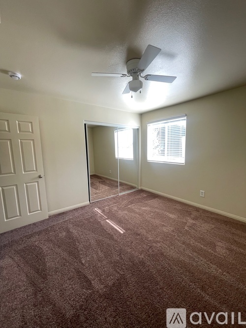 A room with a fan and carpeted floor.