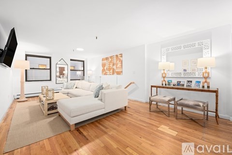 A living room with a white couch and wooden floors.