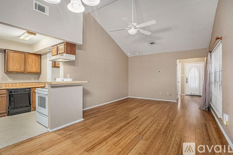 A kitchen with wooden floors and a white ceiling fan.