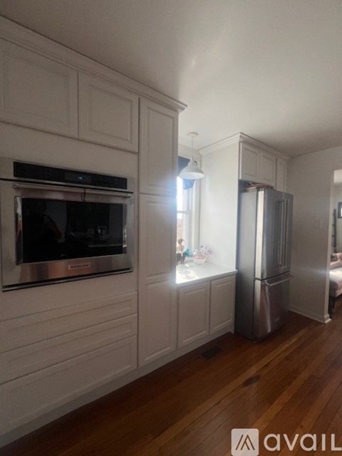 A kitchen with white cabinets and a stainless steel refrigerator.