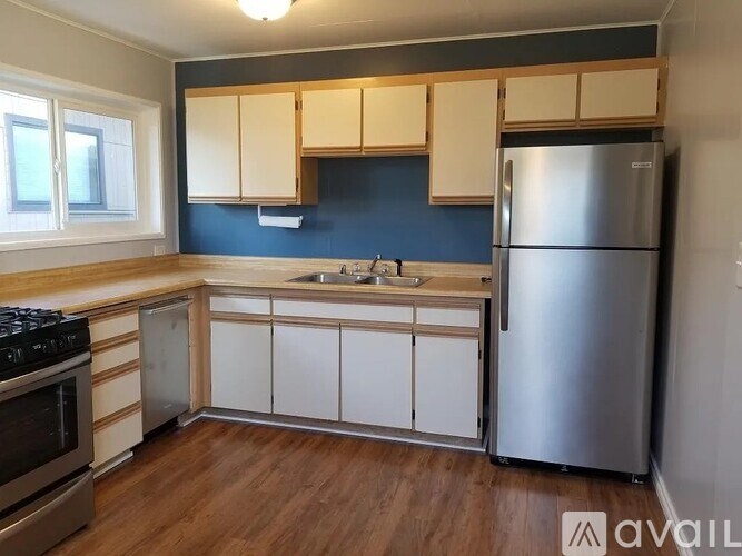 A kitchen with a stove, sink, and refrigerator.