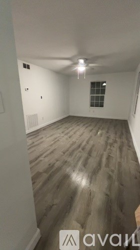 A room with wooden flooring and a window with bars.