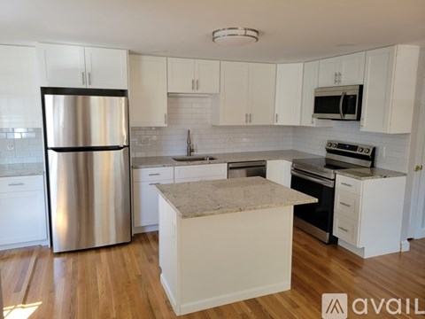 A kitchen with a stainless steel refrigerator and white cabinets.