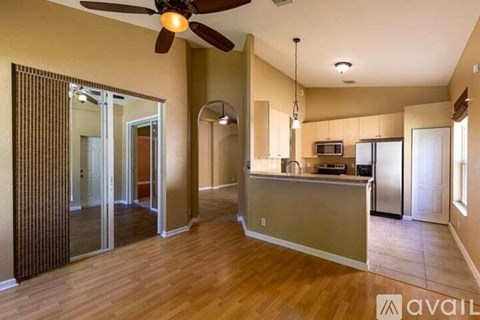 A kitchen with a fan and wooden floors.