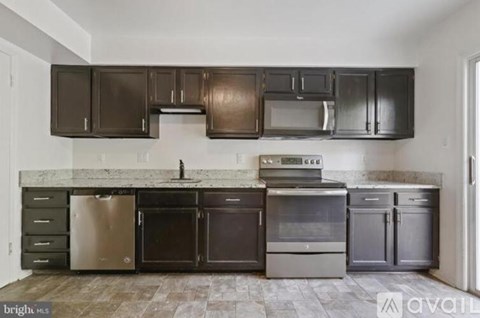 A kitchen with dark brown cabinets and stainless steel appliances.