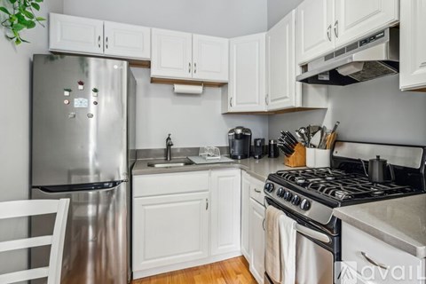 A kitchen with white cabinets and a stainless steel refrigerator.