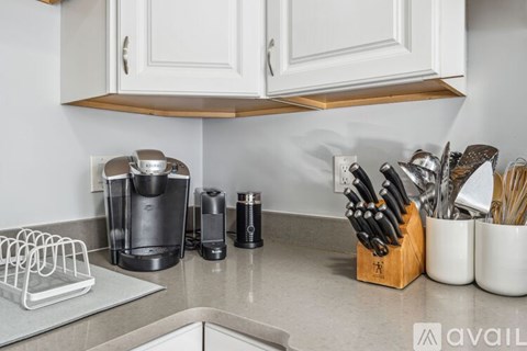 A kitchen counter with a coffee maker, knives, and utensils.