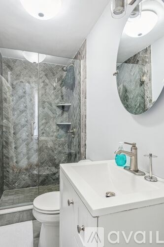 A bathroom with a marble shower and a white toilet.