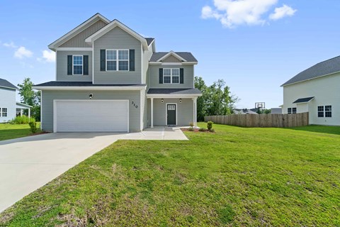 A two-story house with a garage is surrounded by a well-maintained lawn.