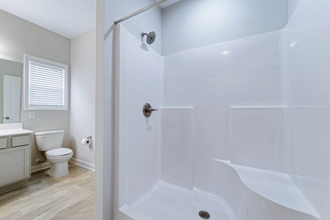 A white bathroom with a toilet, sink, and shower.
