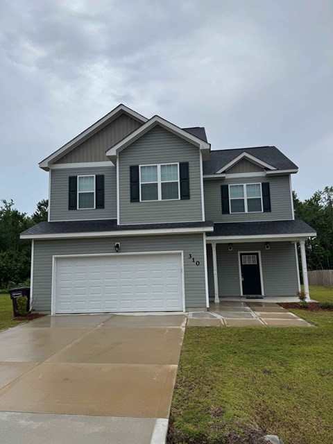 A two-story house with a garage and a driveway.