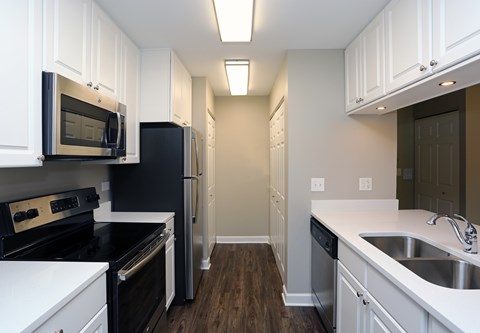 A kitchen with black appliances and white cabinets.