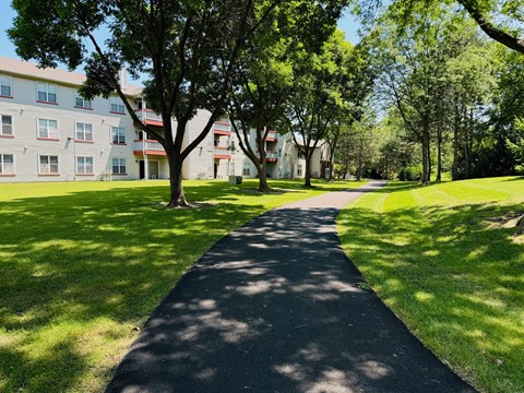 A tree-lined pathway in front of a building.