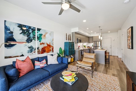 A living room with a blue couch and a painting on the wall.