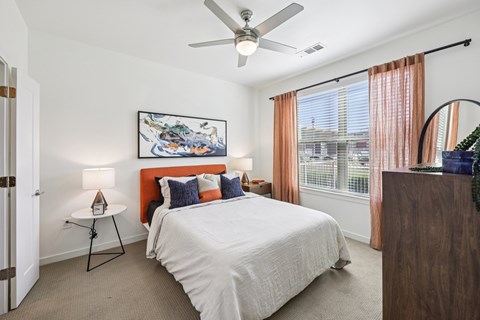 A bedroom with a large bed and a ceiling fan.