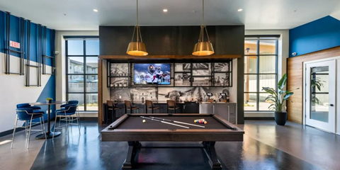 A billiard table is in the middle of a room with a television and a pool table.