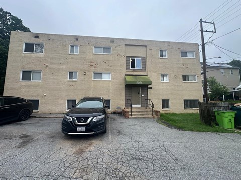 A Nissan SUV is parked in front of a brick apartment building.
